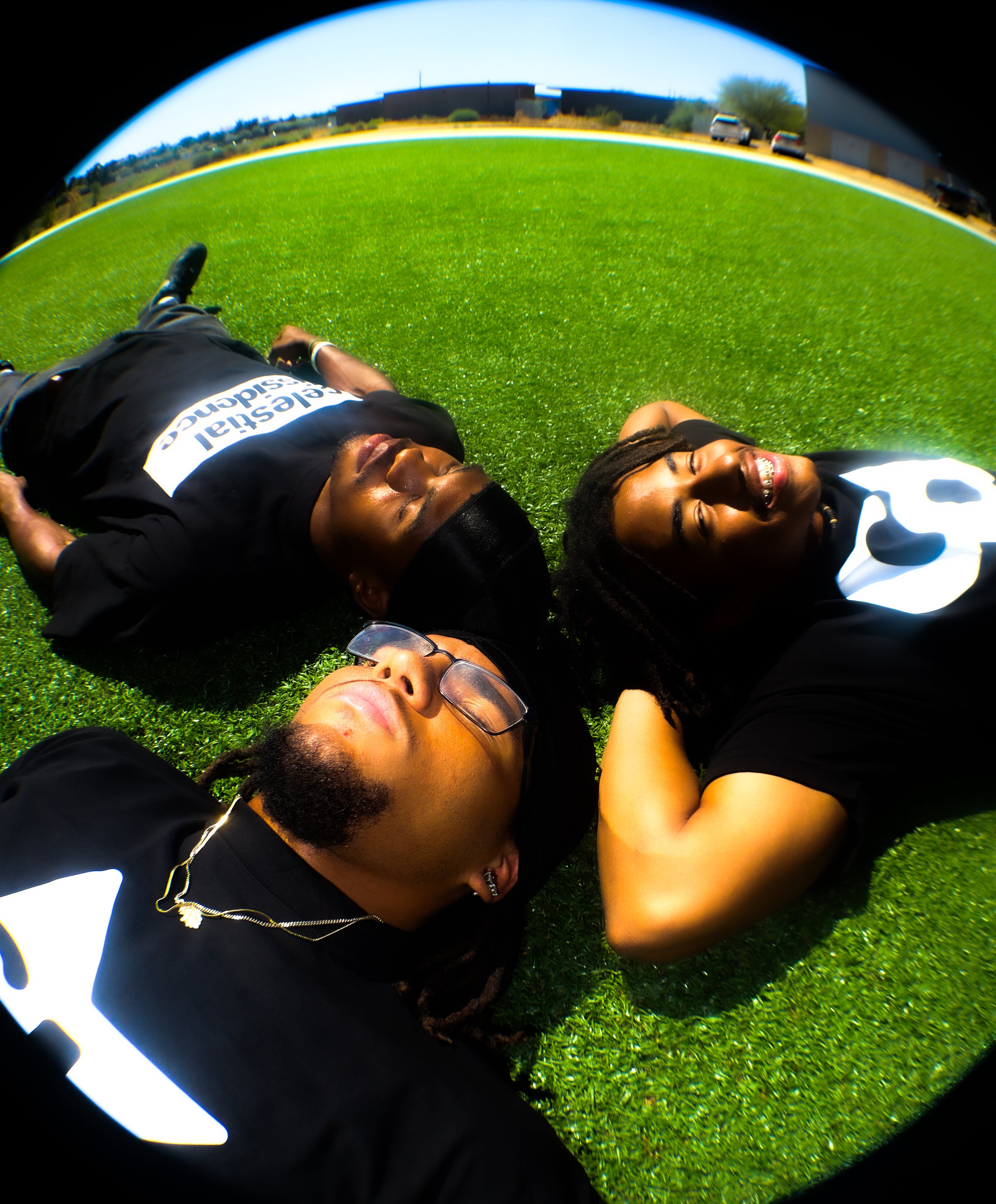 Three people lying on grass with a wide-angle lens effect